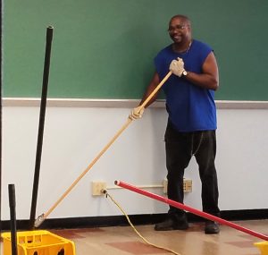 Yonkers School District Unit member Lee Campbell, a custodial worker at Saunders Trades and Technical High School, strips a classroom floor as part of the summer refurbishments at the school.