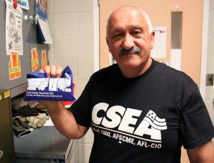 Jim Cross, in his office at Wadsworth Center, shows the naloxone nasal injection kit he received at a CSEA training.