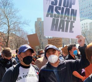 State DMV Motor Vehicle Licensing Examiner Michael Ko, holding sign, participates in a recent rally against Asian hate along with a friend. (Photo provided)