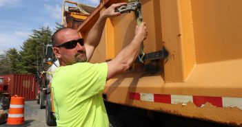 Corey Tilley, a heavy equipment operator at the Town of Queensbury, tightens down a strap on a truck at the town garage.