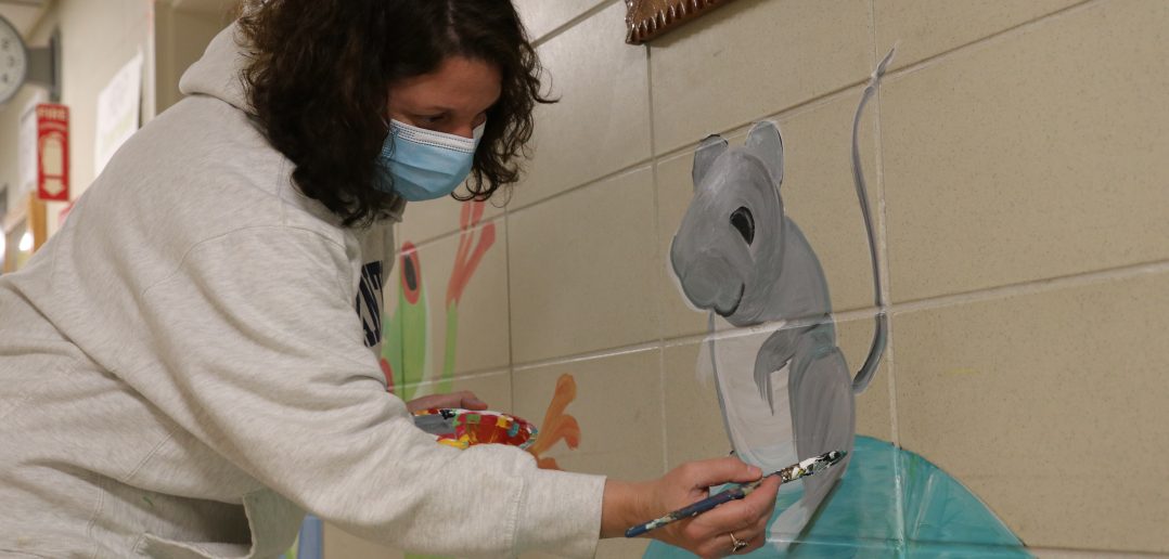 Christina Adams, who has always been artistic and creative, paints a mural on the walls of the St. Lawrence County DSS building during time off from work.