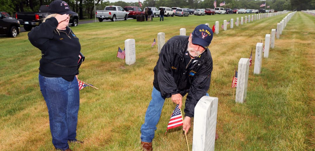CSEA Long Island Region Veterans Committee Chair Maryann Phelps, left, salutes as committee member Steve Abramson plants a flag beside a gravesite at Calverton National Cemetery as part of the committee’s annual Memorial Day Flag Placement, when committee members, guests and community members place flags at the graves of CSEA affiliated individuals who served in the Armed Forces.