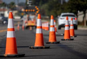 Traffic cones on road with electronic arrow pointing to the right to divert traffic and white car in distance